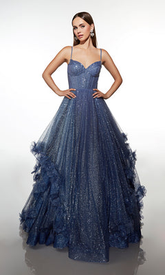 A woman poses with hands on hips in the Alyce 62032 long prom dress, featuring thin straps, a fitted corset bodice, glitter tulle, and ruffled details along the sparkling blue skirt.