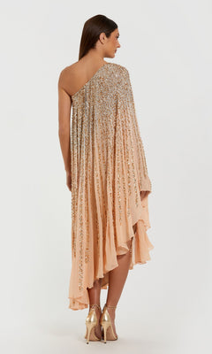 A woman stands facing away, wearing the Mac Duggal 6204 Tea-Length Party Dress in peach with gold embellishments and metallic heels against a plain white background.