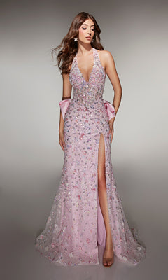 A woman models the Alyce 62044, a long pink prom dress with sequin embellishments, deep neckline, thigh-high slit, and statement satin bow at the back, standing against a plain background.