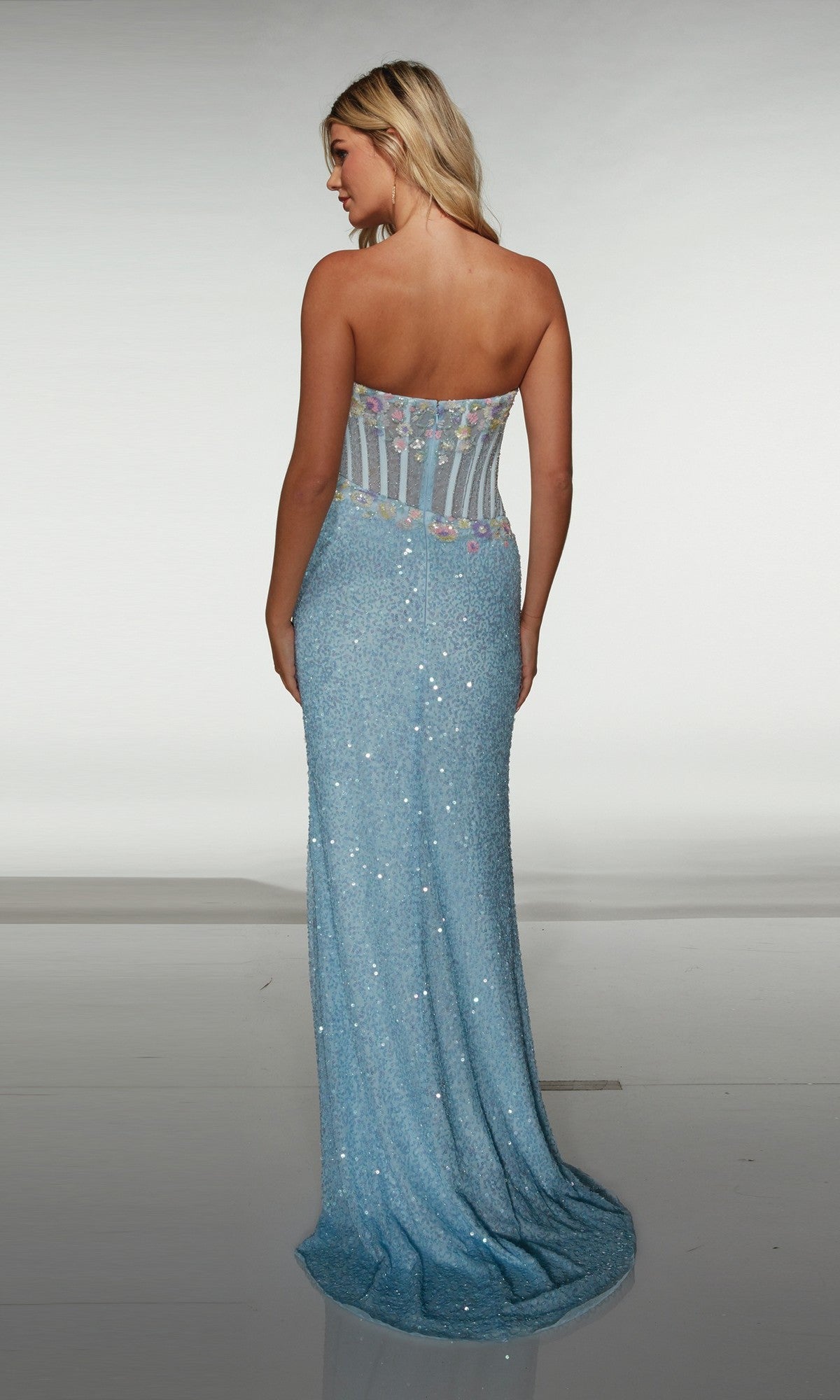 Woman facing away from the camera wearing the Alyce 62047: a strapless, floor-length blue prom dress with a fitted sheer back bodice featuring floral appliques.