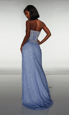 A woman stands facing away, wearing the Alyce 62047 long prom dress—strapless with a floor-length light blue sequin wrap-style skirt and floral bodice details.