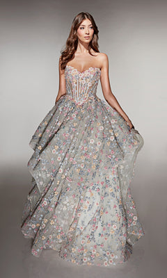 A woman wearing the Alyce 62048 long prom dress, a strapless ball gown with a sheer corset bodice and a full skirt decorated with multicolored floral applique embroidery.