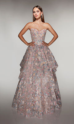 A woman stands against a neutral background wearing the Alyce 62048 long prom dress in French Pink, featuring a strapless fitted corset bodice, layered skirt, pastel floral pattern, and sheer details.