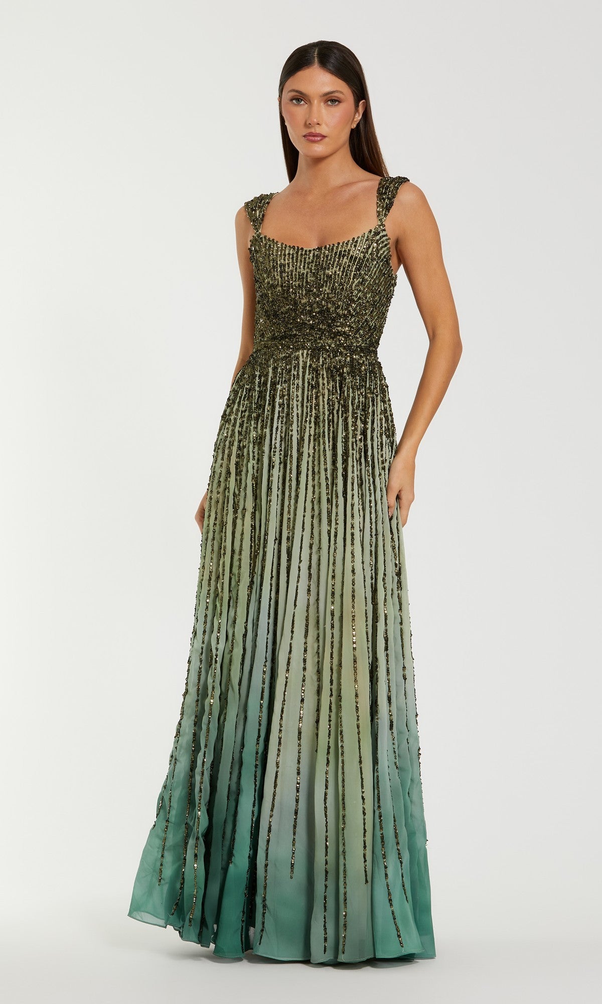 A woman wears the Mac Duggal 6205 Long Formal Dress in Patina Green, a sleeveless, floor-length gown featuring a beaded bodice and striped embellishments, set against a plain light background.