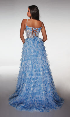 A woman wearing the Alyce 62052 Long Prom Dress, a light blue gown with a ruffle A-line skirt and semi-sheer corset bodice with lace-up back, stands against a plain backdrop.