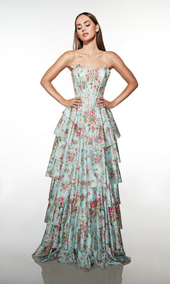 A woman poses with hands on hips, wearing the Alyce 62066 long prom dress—strapless, light blue with pink florals, featuring a corset bodice and tiered ruffle skirt—against a plain white backdrop.