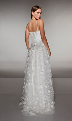 A woman stands facing away, wearing the Alyce 62072 long formal dress—a white sleeveless gown with a corset bodice and 3D floral-lace appliques.