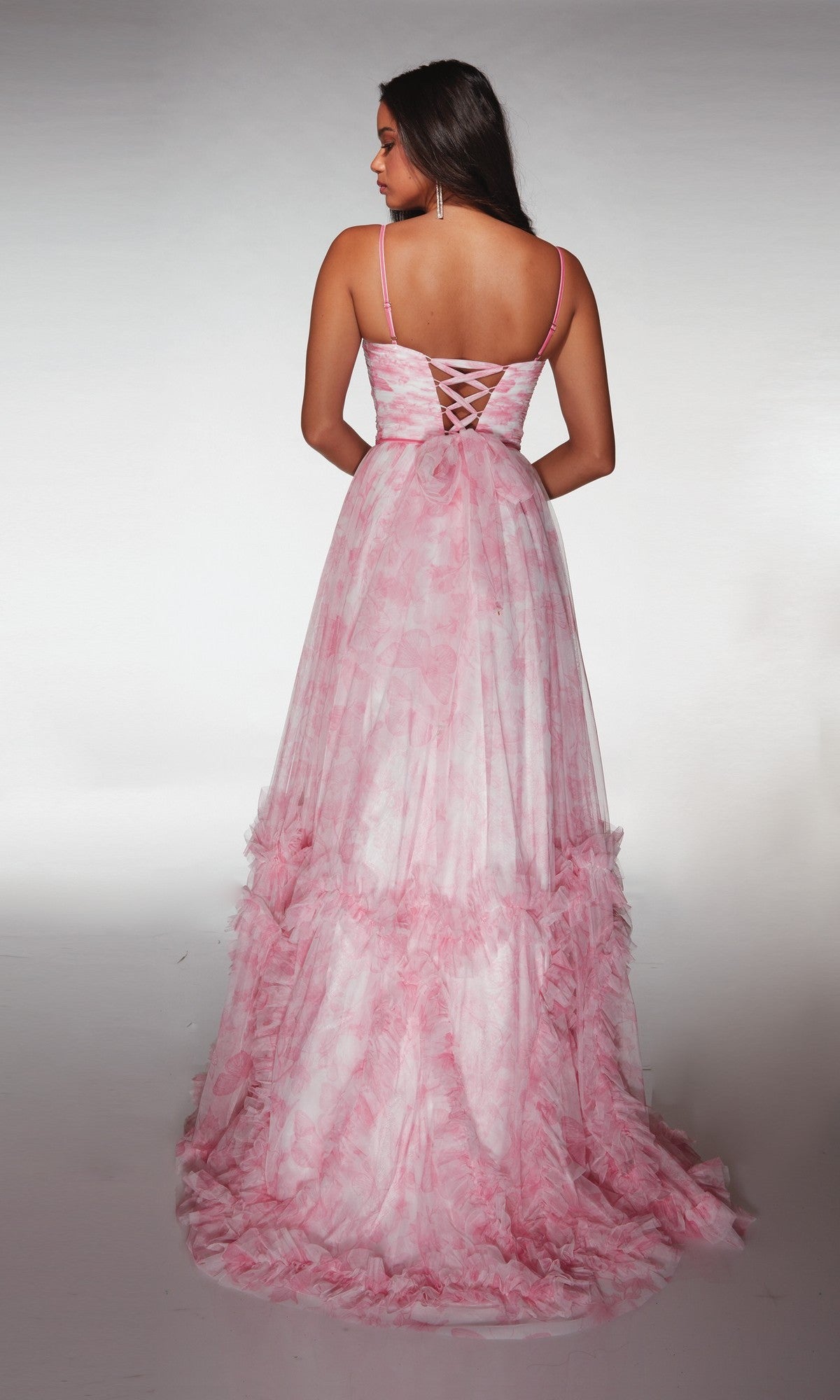 A woman faces away, modeling the Alyce 62078 Long Prom Dress—a pink sleeveless ball gown with spaghetti straps, lace-up back, ruched bodice, and a floor-length tiered tulle skirt—set against a simple light background.