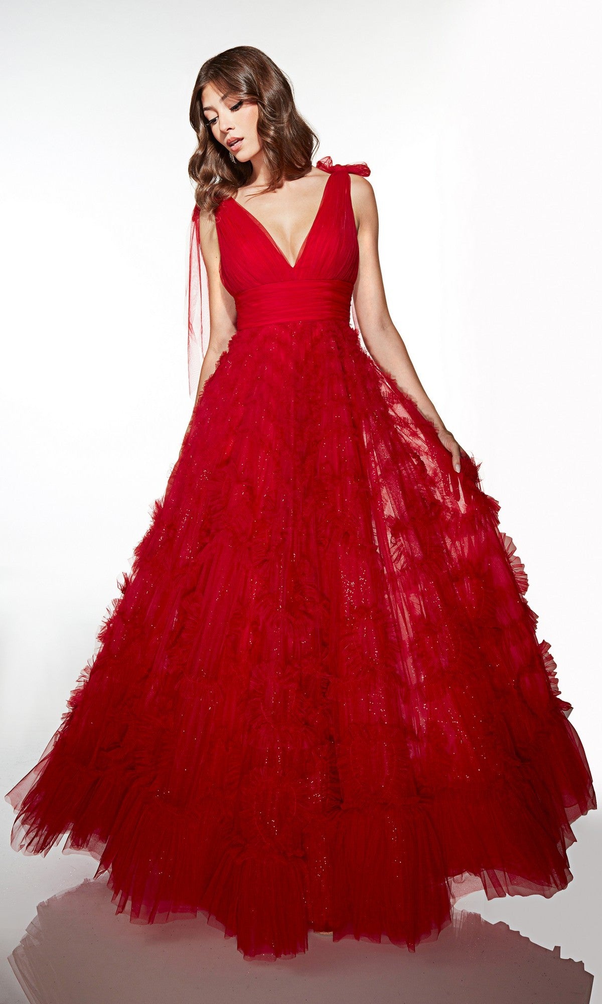 A woman wearing the Alyce 62079 Long Prom Dress in Red Velvet, featuring a sleeveless design, deep V-neckline, and full layered A-line floor-length skirt, stands against a plain white background.