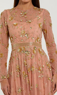 A woman wearing the Mac Duggal 6208 Tea-Length Party Dress—a long-sleeved peach floral dress adorned with gold embroidery and elegant embellishments, making it an ideal choice for a wedding guest.