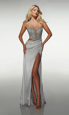 A woman wears the Alyce 62087 Long Prom Dress in platinum—a strapless gown with a beaded corset and high leg slit—standing against a plain, light background.