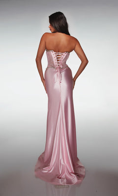A woman stands with her back to the camera, wearing the Alyce 62089— a long prom dress in pink satin with a strapless lace corset bodice and elegant lace-up back detailing.