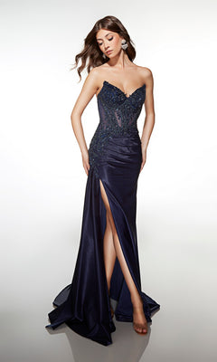 A woman in the navy Alyce 62092 long prom dress, featuring a strapless beaded-lace corset bodice and high-leg slit, stands against a white background looking down with one leg forward.