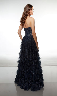 A woman faces away in the Alyce 62096 long formal dress, featuring a strapless embellished corset bodice and sparkly ruffle-tiered tulle skirt in navy blue, set against a plain white background.