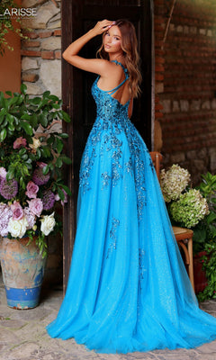A woman poses outdoors by potted flowers and a brick wall, wearing the Clarisse Designs 62118—a bright blue, floor-length A-line glitter tulle prom dress with floral details and a corset-style bodice.