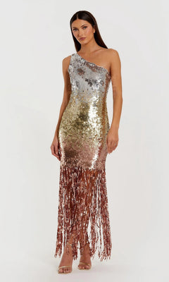 A woman wears the Mac Duggal 6212 long formal dress, a one-shoulder gown in metallic gold and silver ombre sequins with fringe at the hem, paired with strappy heels.