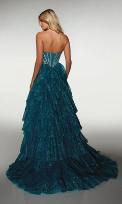 A woman with blonde hair wears the Alyce 62144 long formal dress, featuring a strapless design and blue glittery tiered ruffle skirt, photographed from the back against a neutral background—a dazzling prom look.