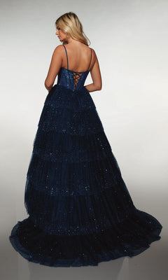 A woman in the Alyce 62146 long formal dress, a navy blue ballgown with a ruffle skirt, thin straps, and a lace-up back, stands against a plain background.