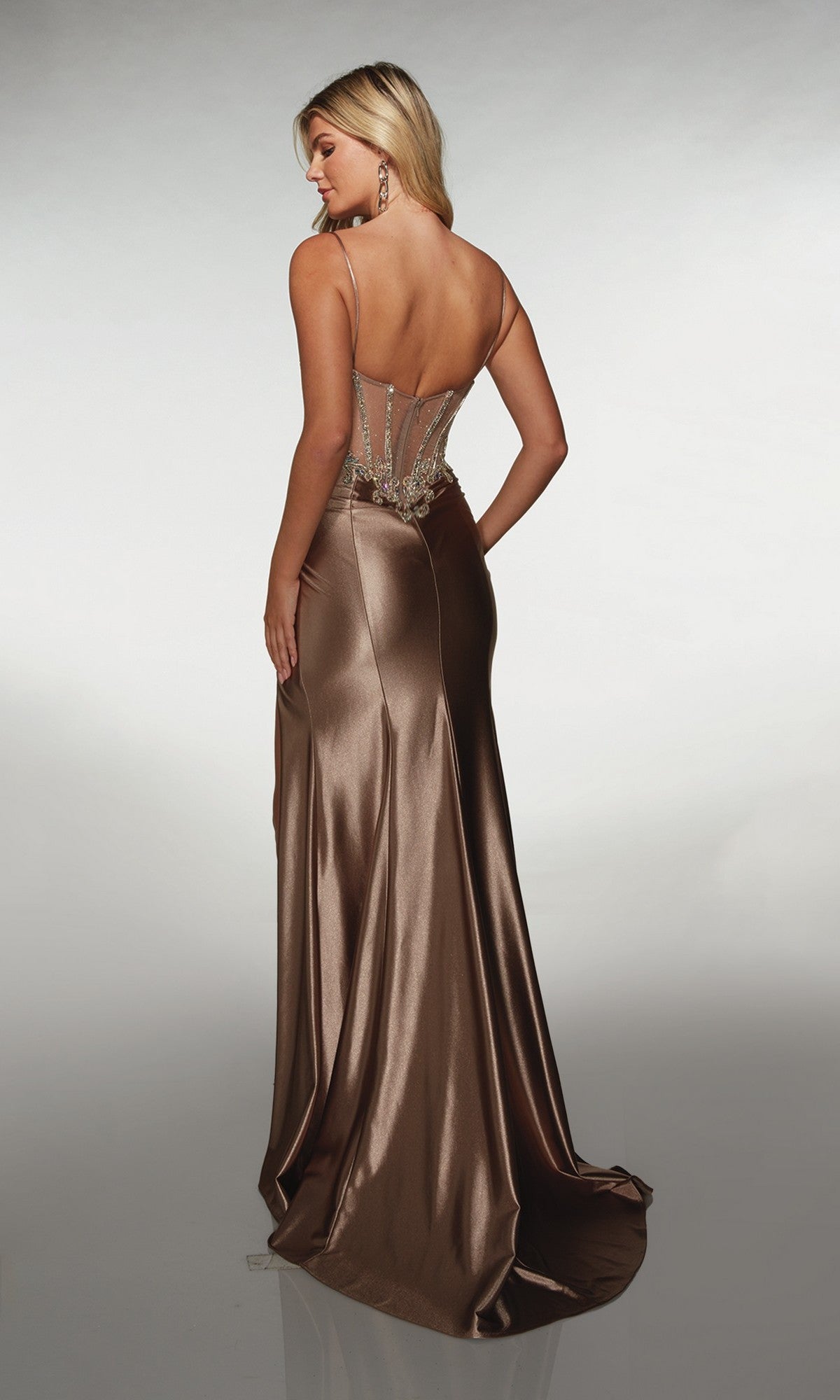 Woman models the Alyce 62154, a bronze long prom dress with a beaded bodice, fitted sheer back, and stretch satin sheath skirt that flows to the floor, standing with her back to the camera against a plain light background.