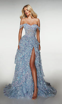A woman poses in the Alyce 62186 long prom dress, a light blue off-the-shoulder A-line gown with a sheer corset bodice, 3D floral appliques, and a high slit, standing against a plain background.