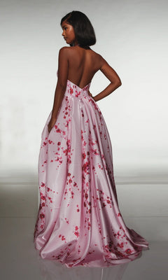 A woman stands with her back turned, wearing the strapless Long Formal Dress: Alyce 62214—a floor-length pink floral satin gown—against a neutral background.