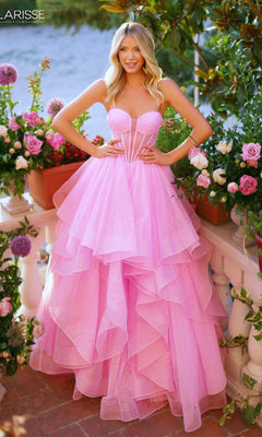 A woman wearing the Clarisse Designs 62263 glitter pink strapless prom ball gown with a corset bodice stands outdoors among blooming flowers and greenery.
