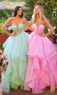 Two women wearing Clarisse Designs 62263 prom ball gowns—one mint green, one pink—stand outdoors, smiling. The strapless dresses feature glitter tulle, sheer panel bodices, and voluminous layered skirts.