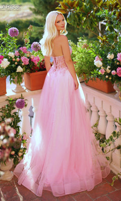 Wearing the Long Prom Dress: Clarisse Designs 62312, a woman in a strapless glitter pink corset gown stands on a balcony among potted flowers, gazing over her shoulder at the camera.