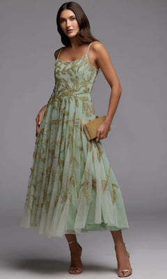 A woman wearing the Mac Duggal 6255 tea-length party dress in seafoam gold, featuring gold beaded embroidery, holds a textured clutch and stands in strappy heels against a plain gray background.