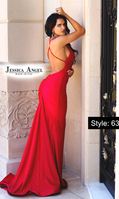 A woman in a bold red, fitted, strappy-back mermaid gown—Jessica Angel Scoop-Neck Long Prom Dress 636—stands by an ornate stone wall and black door.
