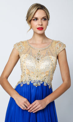 A woman wearing the Juliet 636 long prom dress, featuring gold embellished cap sleeves, sheer detailing, and a royal blue a-line skirt, looks to the side against a plain background.