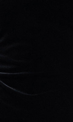 A dark surface with subtle, wavy light reflections and faint highlights evokes the soft texture of the Blondie Nites 6381BN Long Sleeve Mini Hoco Dress, featuring delicate feathered cuffs, creating an elegant and sophisticated backdrop that complements this affordable black homecoming dress.