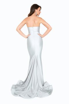 Woman in a silver Ruched-Waist Strapless Long Prom Dress (6538H), floor-length with a slight train, stands with hands on hips and faces away from the camera.
