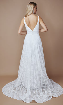 A woman faces away in the Nina Canacci 6617 long formal dress—a sleeveless white gown with an A-line skirt, deep V-back, and flowing train—standing against a plain beige background.