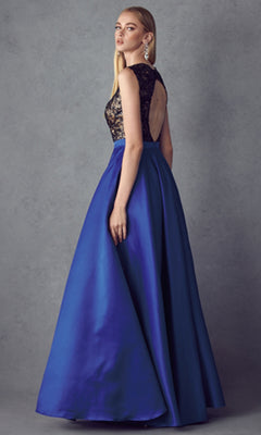 A woman poses against a gray background wearing the Juliet 661 Cut-Out Long A-Line Prom Dress, featuring an embellished black lace bodice, open back, and flowing royal blue satin skirt.