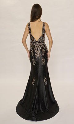 A woman wearing the Nina Canacci 6633 long formal dress, featuring metallic floral embellishments and rhinestone details, stands with her back to the camera against a plain background.