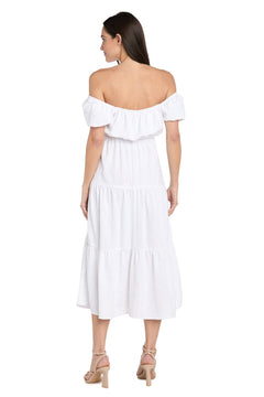 Woman stands with her back to the camera, wearing the R&M Richards 6669 Tea-Length White Party Dress featuring ruffled off-the-shoulder sleeves and a midi hem—ideal for special occasions. She's styled with beige heeled sandals.