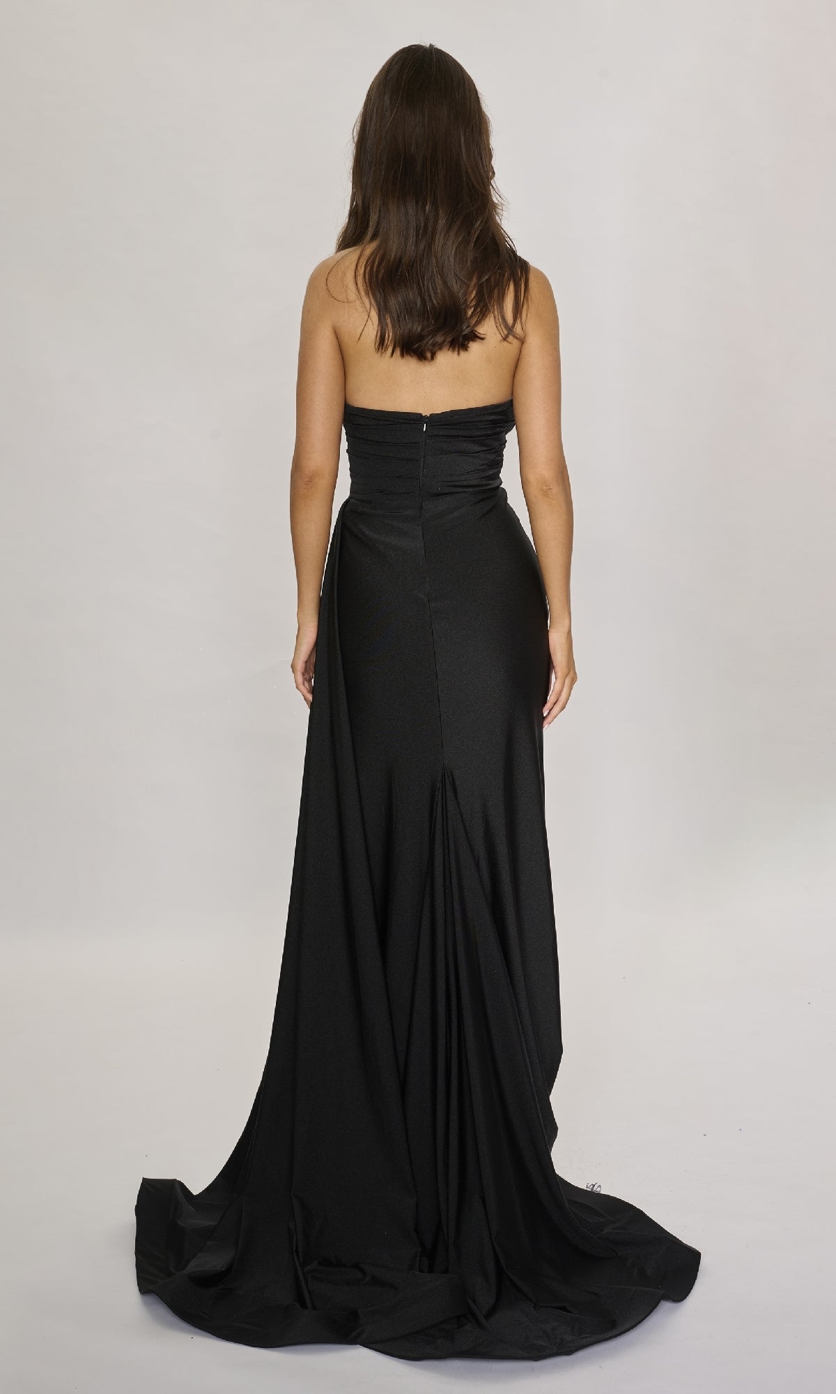 A woman with long brown hair, wearing the Nina Canacci 6686 long formal dress featuring a strapless sweetheart neckline, stands facing away against a plain light background.