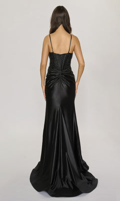 A woman with long brown hair is seen from behind wearing the Nina Canacci 6687—a black, floor-length formal dress featuring rhinestone embellishments—against a plain light background.