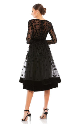 Woman viewed from the back in the Mac Duggal 67007 knee-length wedding-guest dress, featuring long sleeves, black sheer overlay, floral embellishments, and paired with black high-heeled sandals.