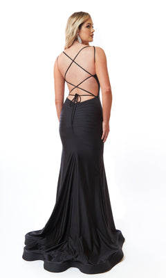 A woman poses in an elegant Square-Neck Long Prom Dress, Atria 6704H, featuring a fitted silhouette, open back, and crisscross straps, against a plain white background.