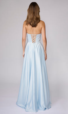 A woman stands with her back to the camera in a strapless light blue Nina Canacci 6718 long formal dress featuring an A-line silhouette and lace-up back.