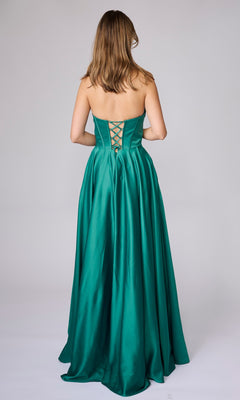 A woman stands facing away in the Nina Canacci 6718 long formal dress, a strapless emerald green satin A-line gown with a lace-up back and floor-length silhouette.