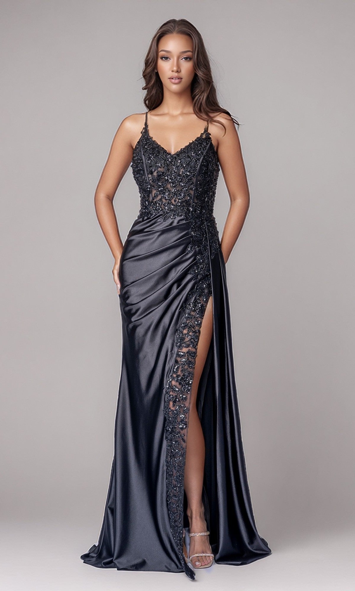 A woman models the Long Formal Dress: Nina Canacci 6722 in black, featuring lace details, spaghetti straps, sequin embroidery, and a high slit, standing against a plain light gray background.