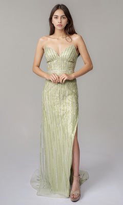 A woman poses against a plain background wearing the Nina Canacci 6723 long formal dress in pistachio—a strapless, floor-length gown with a high slit and sparkling linear beading.