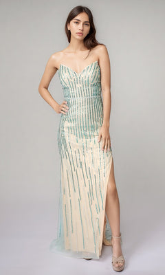 A woman in the Nina Canacci 6723 long formal dress in nude/teal, featuring a strapless design with linear beading, a sheer overlay with vertical teal sequins, and a thigh-high slit, stands against a plain background.