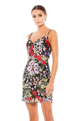 A woman stands against a plain white background wearing the Mac Duggal 67459 short floral-print party dress, featuring a strappy back and vibrant floral embroidery.
