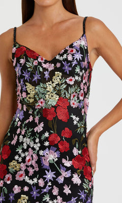 Woman wearing the Mac Duggal 67473: a long formal dress with colorful red, purple, white, and green floral embroidery, thin straps, and a V-neckline.