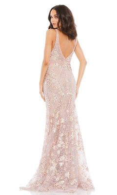 A woman stands with her back to the camera wearing the Mac Duggal 67481, a sleeveless, floor-length light pink formal dress with floral prints.