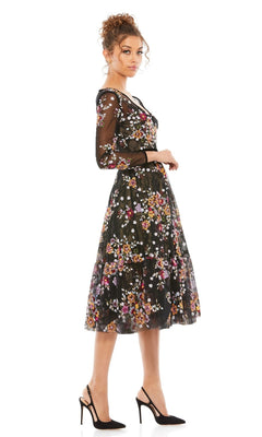 A woman stands in profile against a white background wearing the Mac Duggal 67499 Print Midi Wedding-Guest Dress with colorful floral embroidery and black heels.